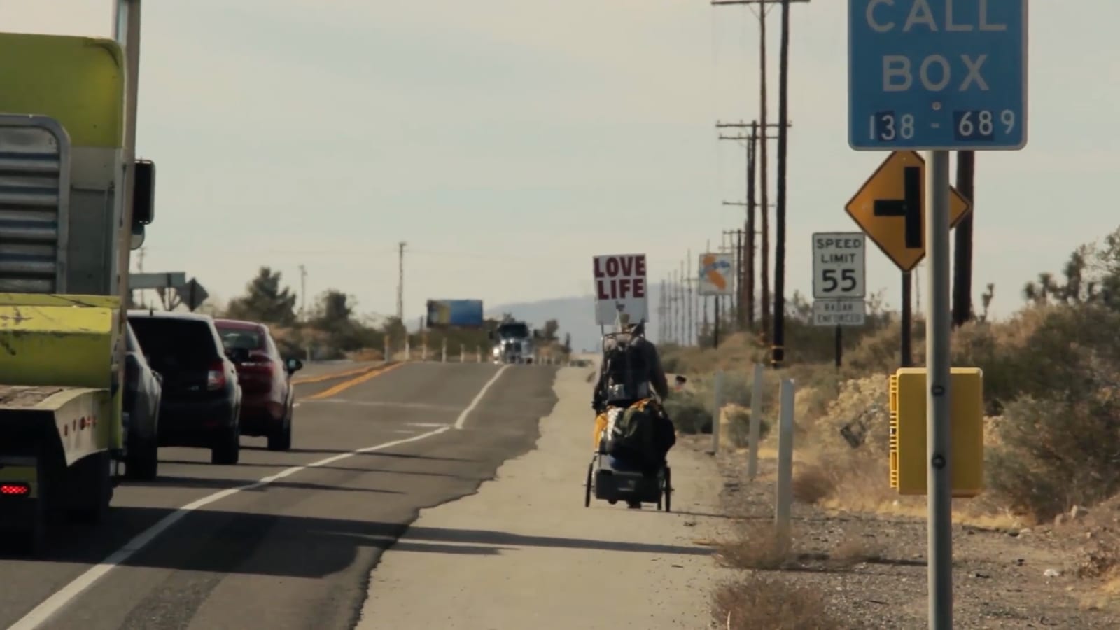 Steve Fugate walking with his LOVE LIFE sign. Still from Trail Therapy (2014).